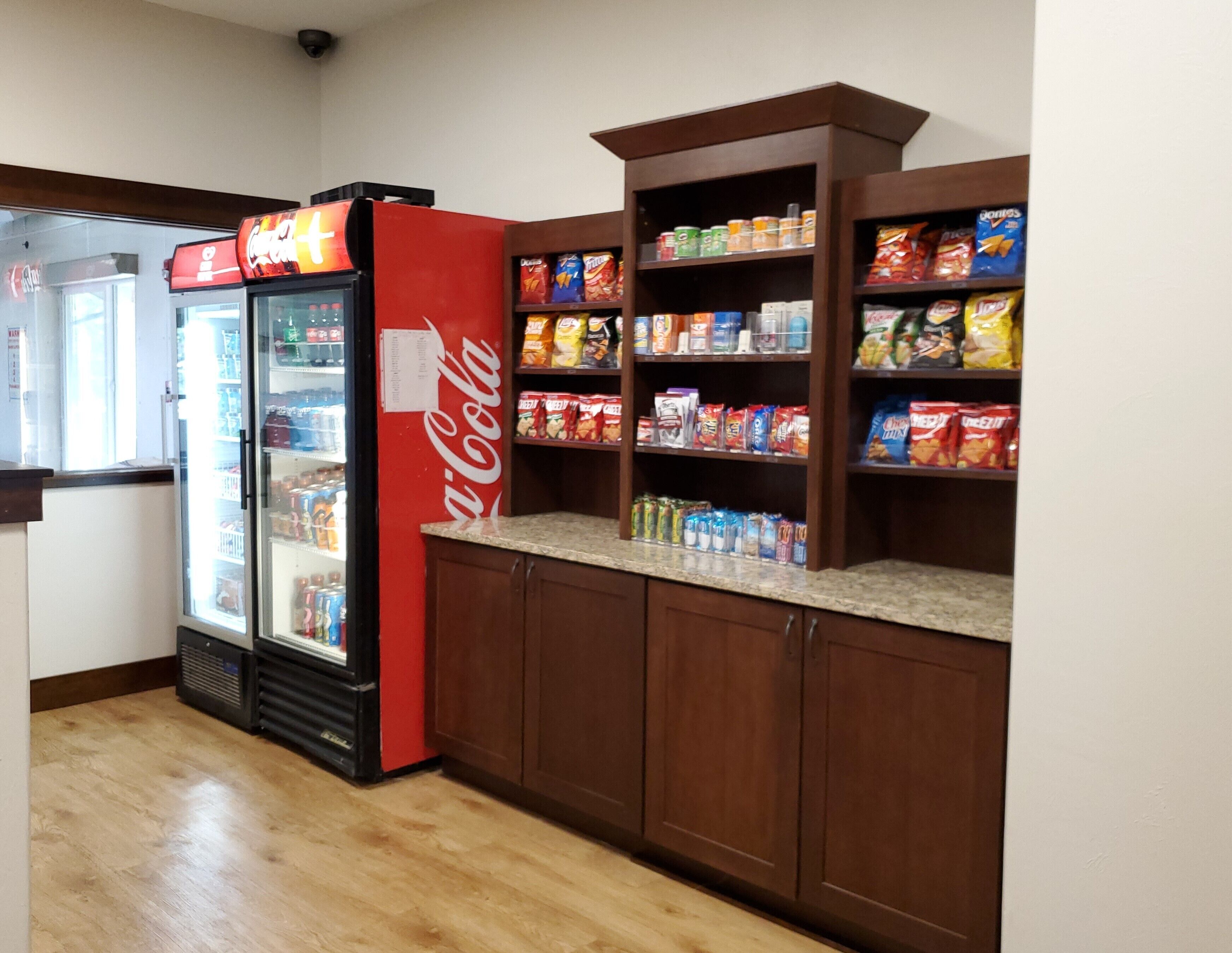 Un bar servant des collations, avec un réfrigérateur rempli de Coca-Cola, des étagères garnies de produits à grignoter et un congélateur.