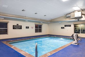 An indoor swimming pool with clear signage, including "NO DIVING" and "NO LIFEGUARD ON DUTY" signs.