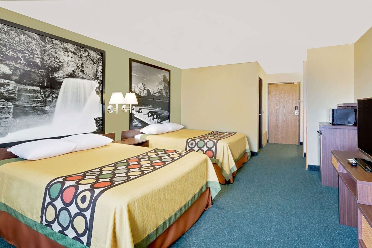 Habitación de hotel con dos camas, un televisor y un escritorio con computadora.