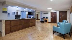 A reception area with a wooden counter, a blue armchair, and a flat-screen TV.