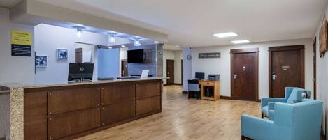 A reception area with a wooden counter, a blue armchair, and a flat-screen TV.