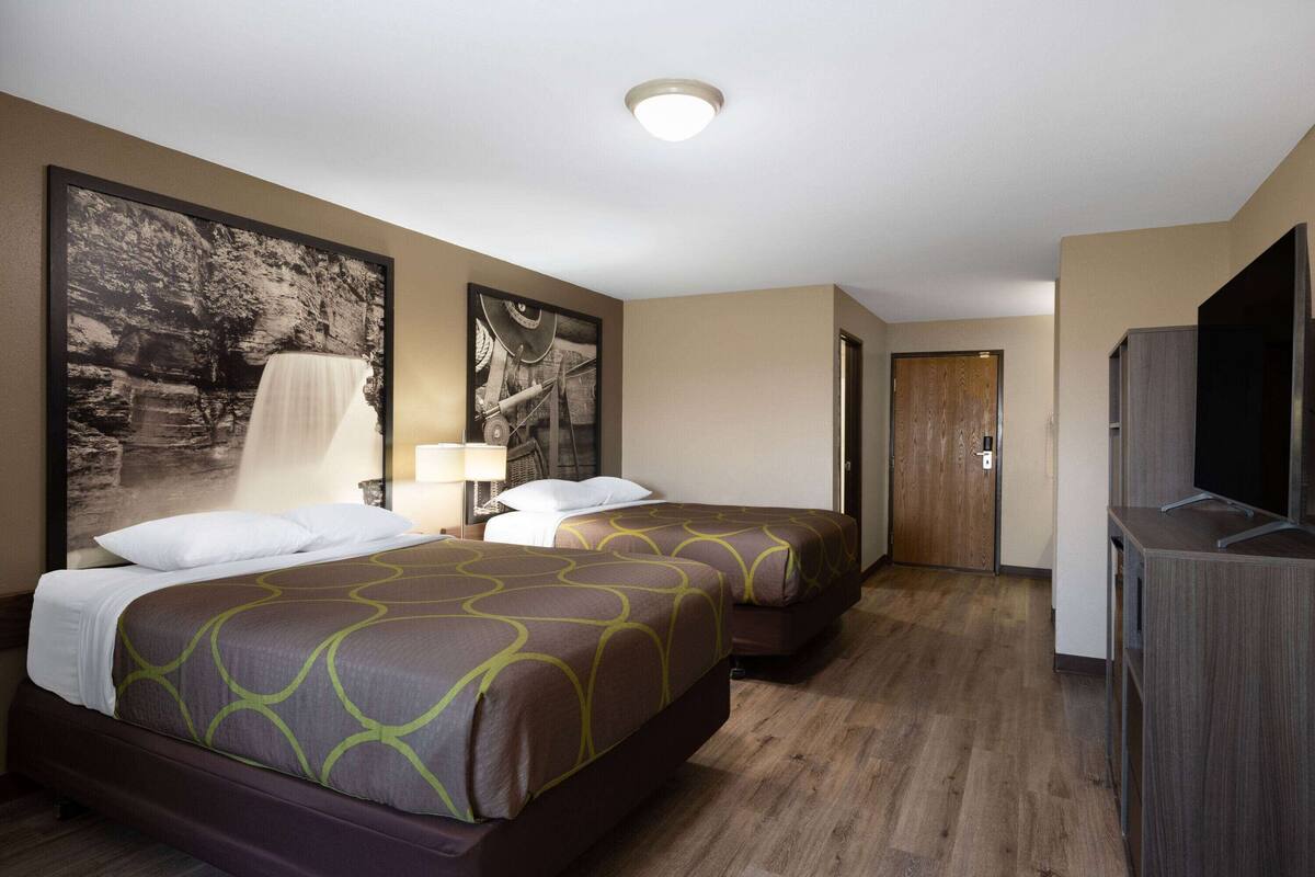 Ett hotellrum med två sängar, en TV och en dörr som leder till ett annat rum.