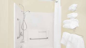 Un baño con ducha, un perchero para toallas y un dispensador de toallas.