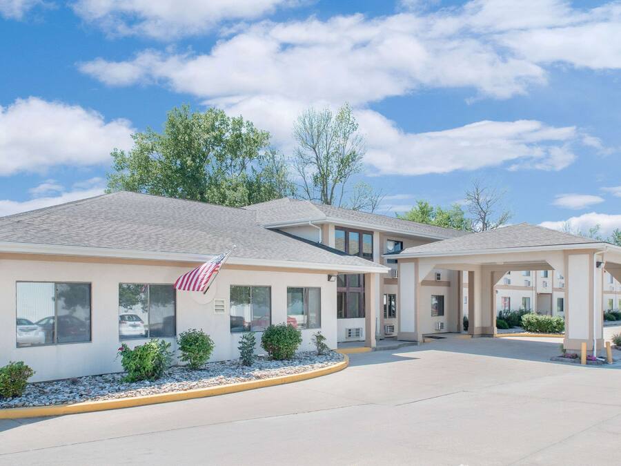 A hotel with a covered outdoor area, multiple windows, and a flag.