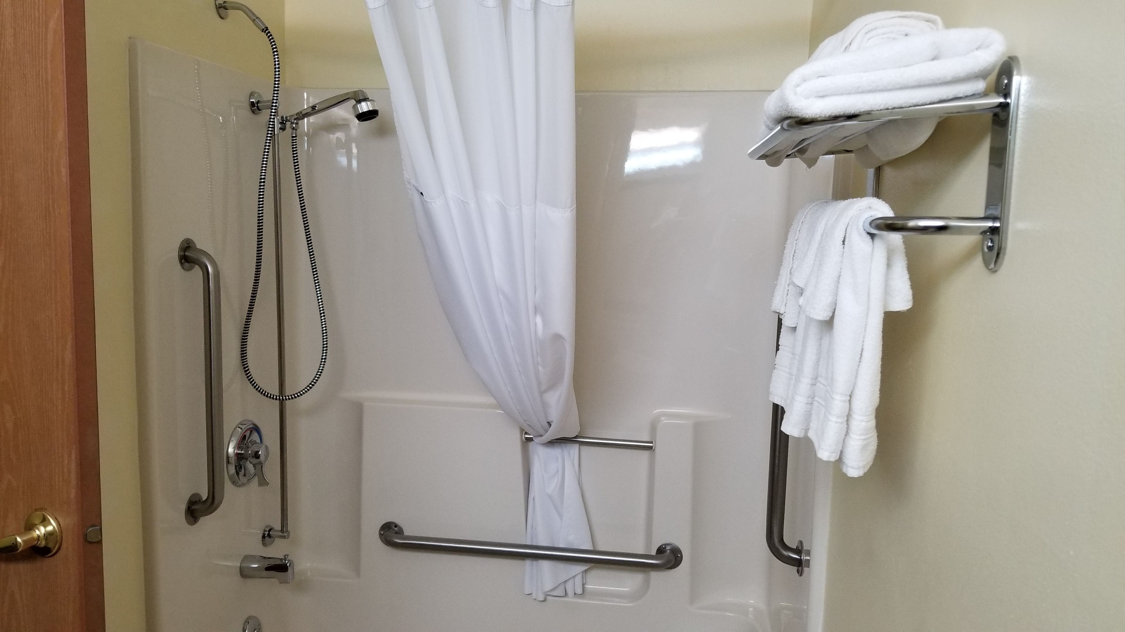 Une salle de bain équipée d’une douche, de barres d’appui et d’un porte-serviettes.