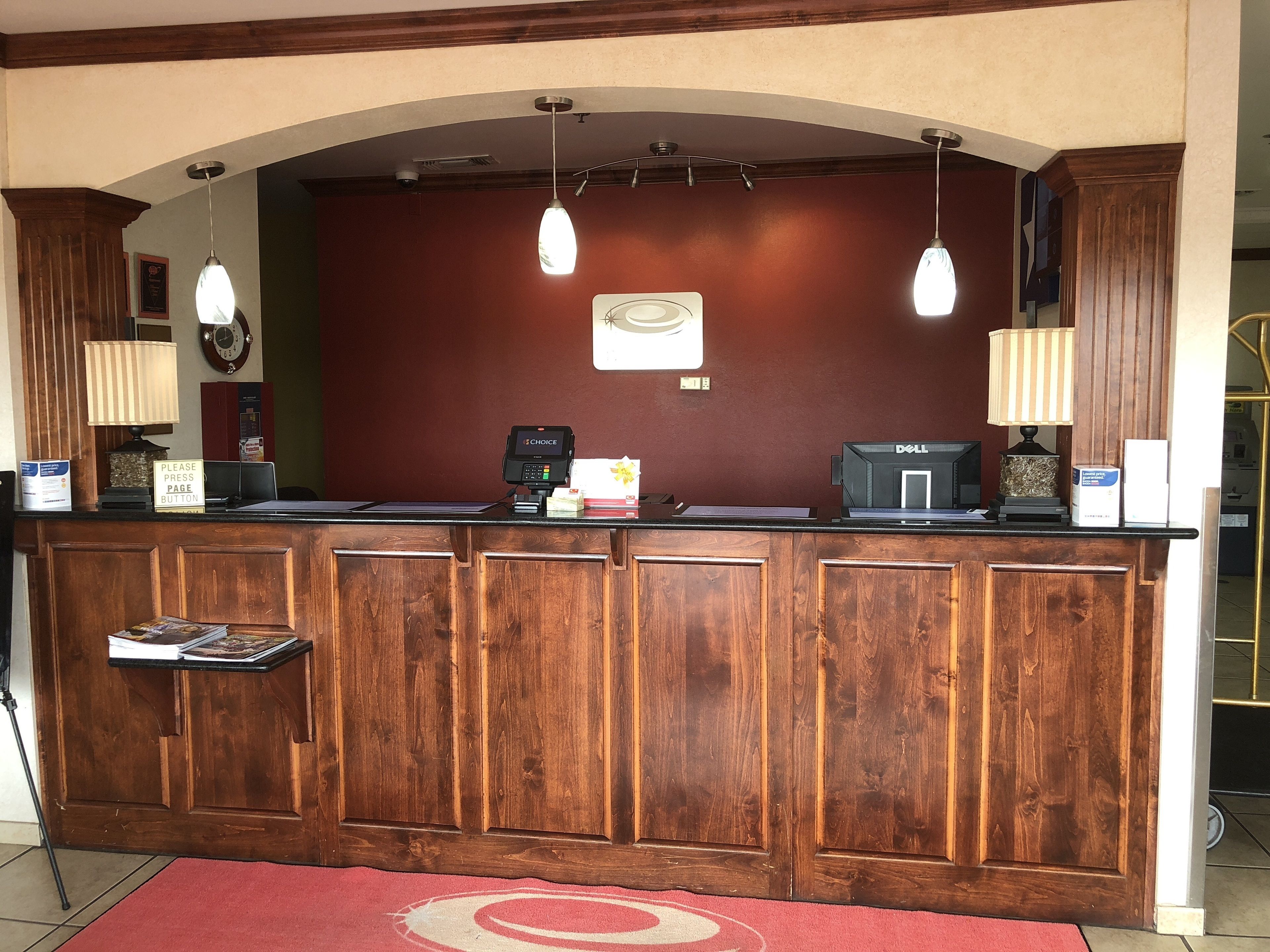 A reception desk with a wooden finish, a clock, and a Dell computer monitor.