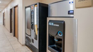 A hallway with ice and vending machines, a 24-hour service sign, and a sign indicating ice and vending services. - Econo Lodge Lubbock I-27 (Lubbock)