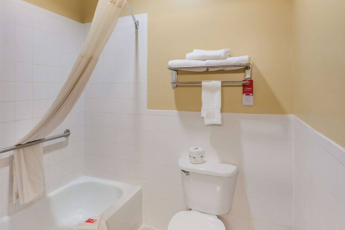 A bathroom with a bathtub, toilet, and towel rack.