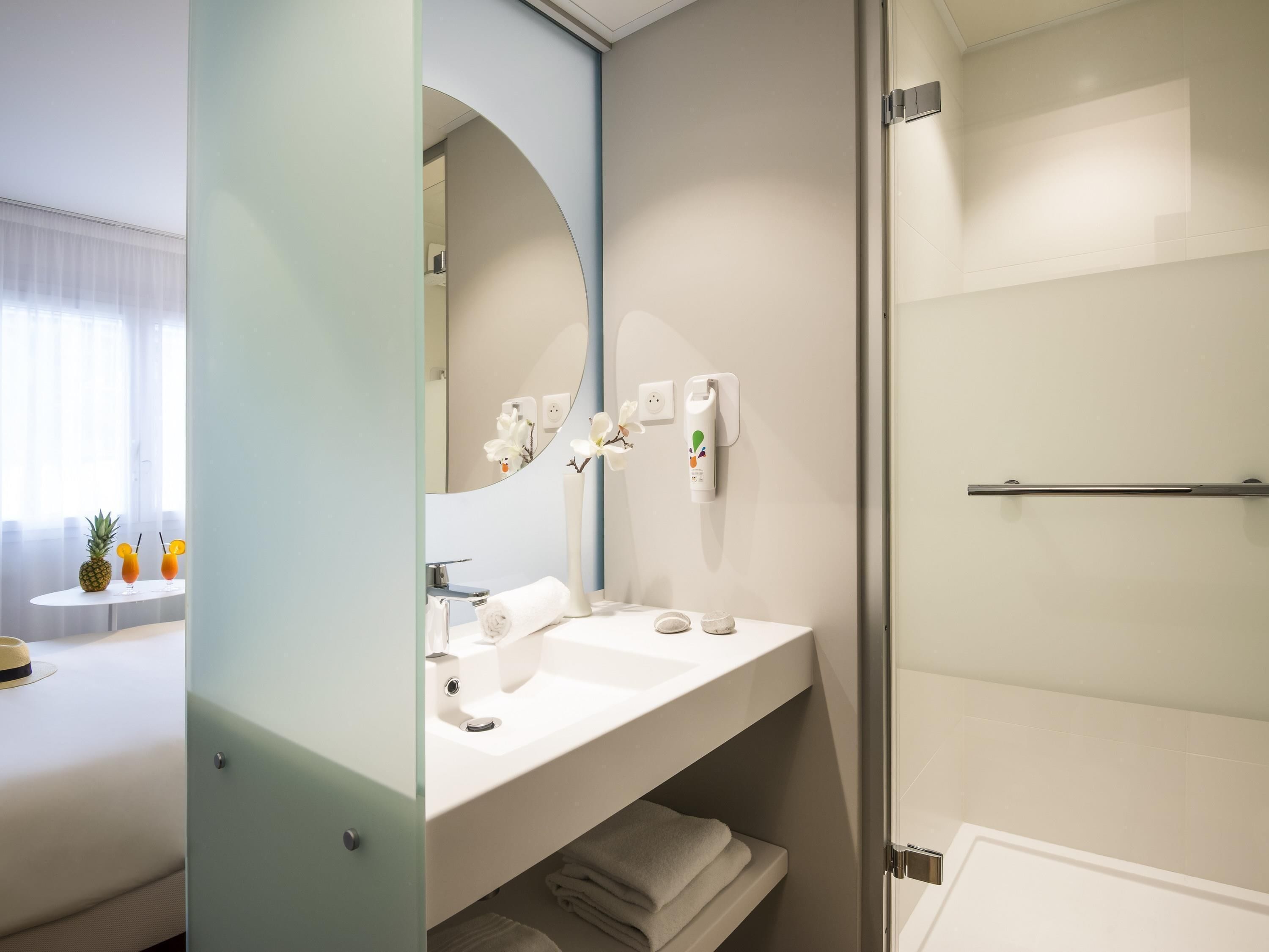 A modern bathroom with a sink, mirror, and shower.
