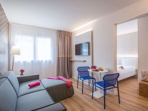 Relax in this stylish room with a comfortable sofa, a flat-screen TV, and a neatly made bed.