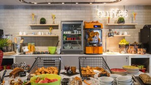 A buffet setup with various food items, a refrigerator, and a coffee machine. - ibis Styles Nice Cap 3000 Airport (Saint-Laurent-du-Var)