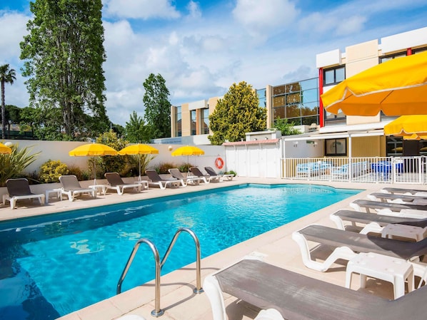 Relax by the pool surrounded by comfortable lounge chairs and shaded by umbrellas.