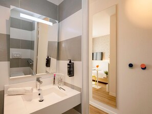 Bathroom features a sleek vanity, geometric tile pattern, and ample natural light.