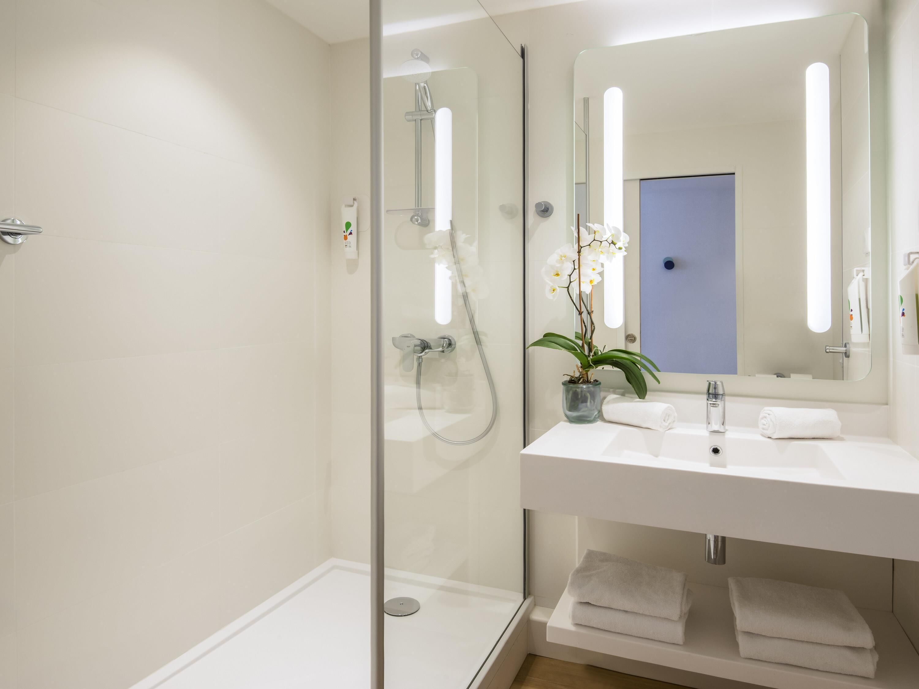 A modern bathroom with a glass-enclosed shower, a white sink, and a mirror.
