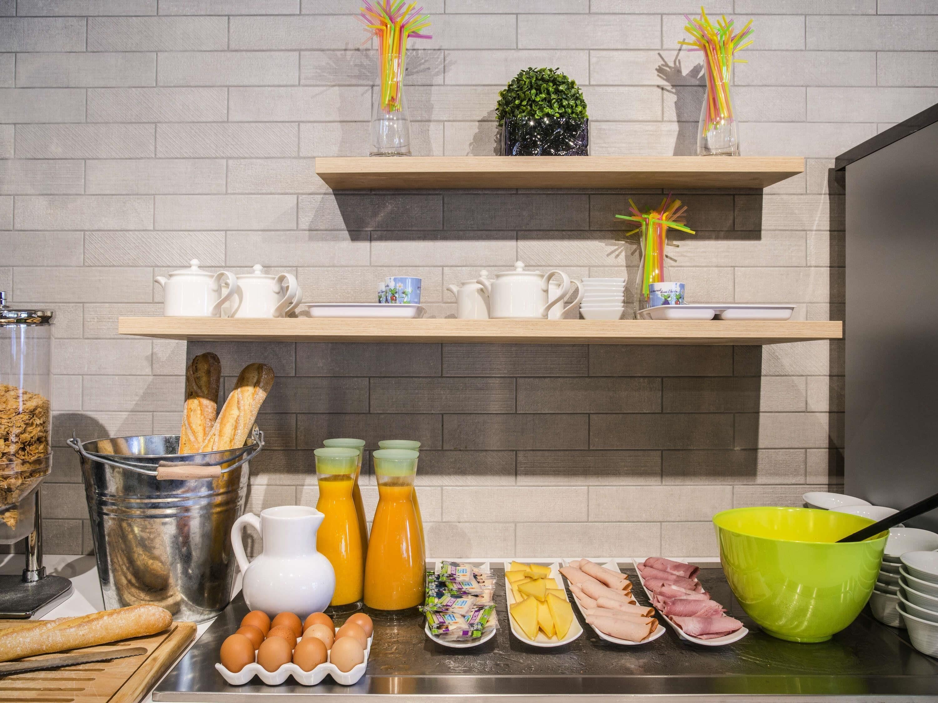 A breakfast buffet with bread, eggs, juice, and various meats.