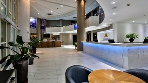 A modern hotel lobby with a reception desk, seating area, and a bar. - SLAVIERO Downtown São Paulo (São Paulo)