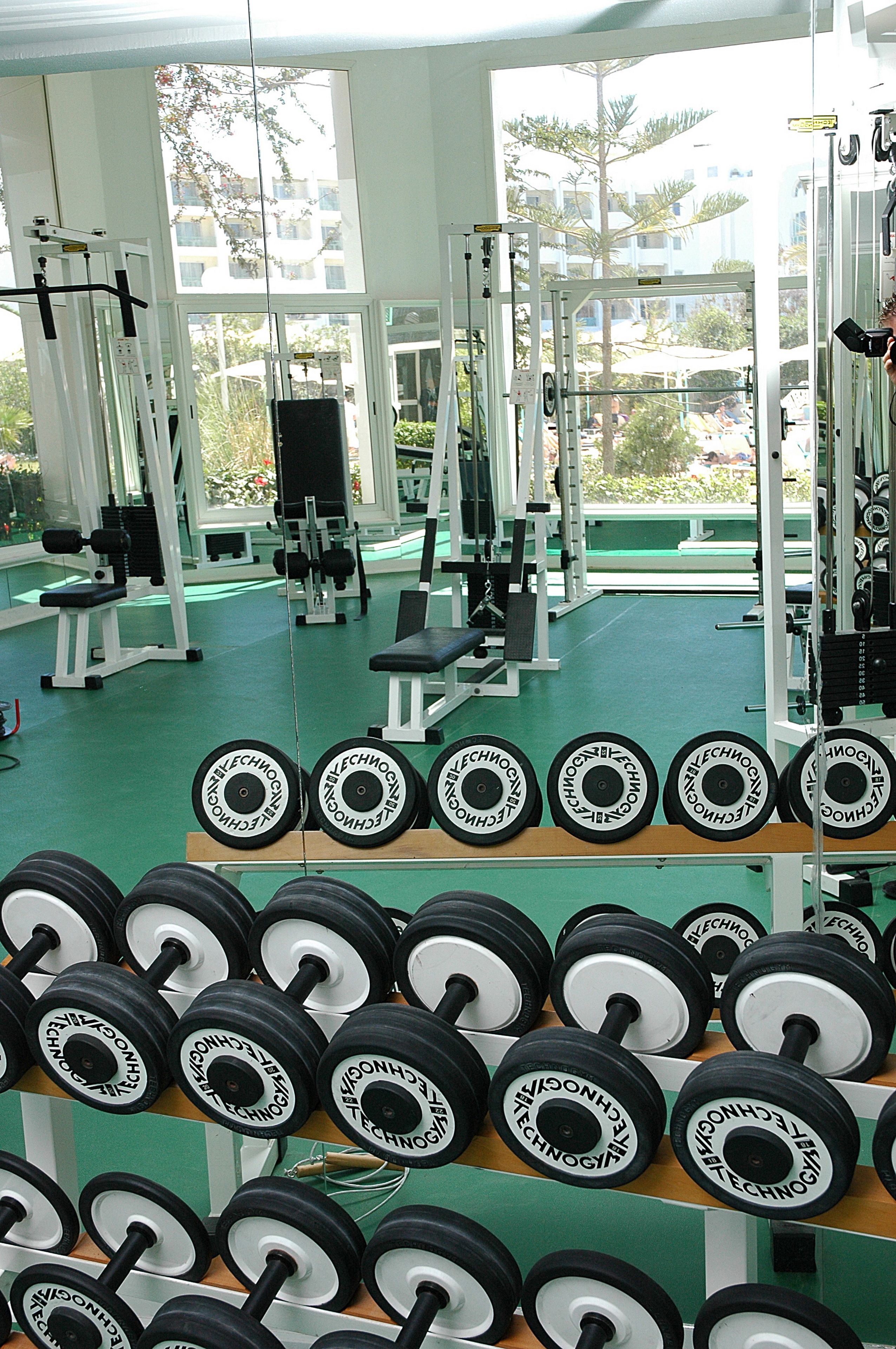 Ein Fitnessraum mit unterschiedlicher Trainingsausstattung und Hanteln, die auf Regalen angeordnet sind.