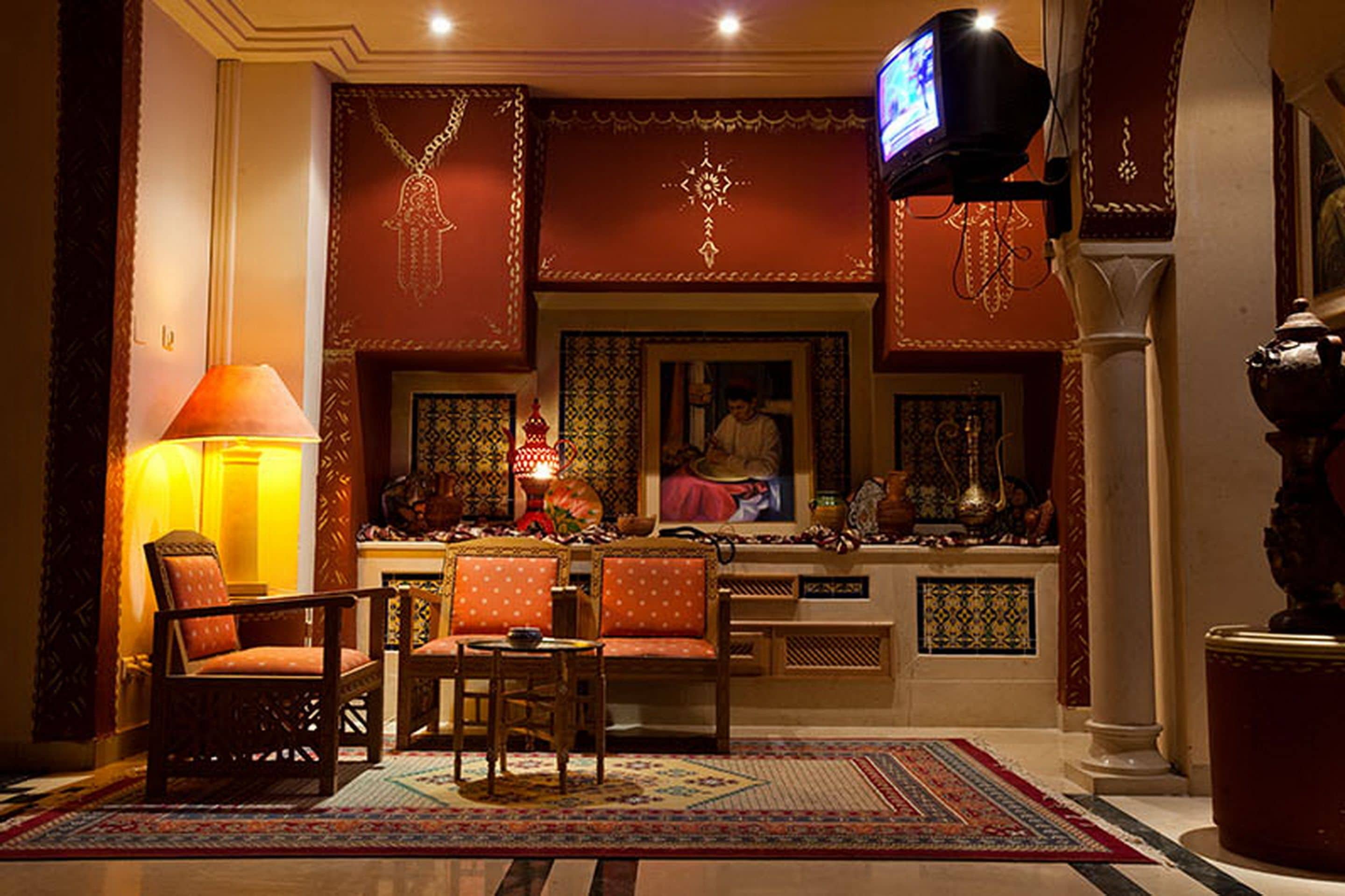 Un interior tradicional con un sofá, sillas, una mesa, una lámpara y un televisor.