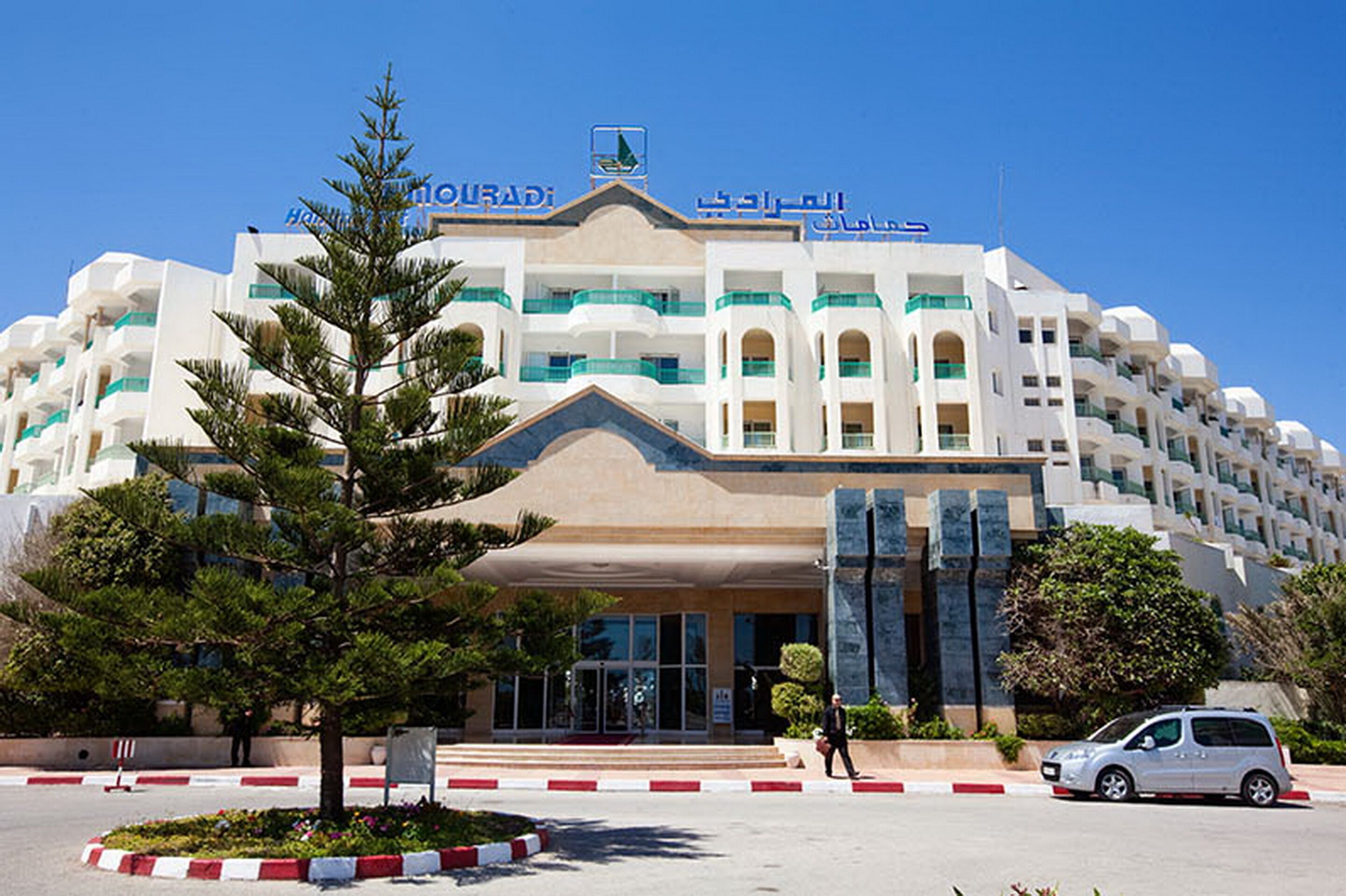 A large, multi-story hotel with a prominent entrance and a sign in Arabic.