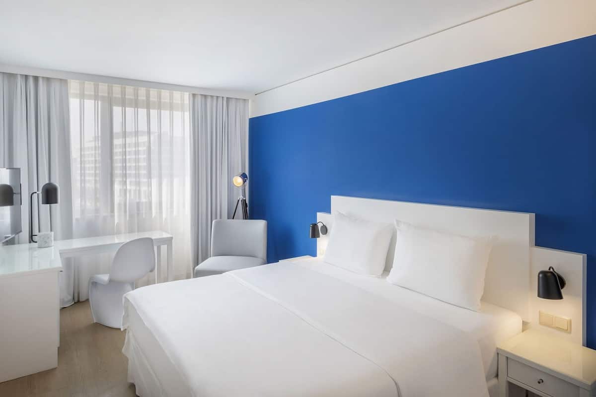 Une chambre d’hôtel équipée d’un lit, d’un bureau, d’une chaise et de lampes de chevet.
