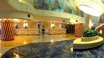 A spacious lobby with a marble floor, a central fountain, and a high ceiling with decorative lighting.