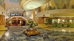 A grand lobby with a marble floor, a central ornate table, and a staircase leading to an upper level. - Grand Hotel La Pace (Sant'Agnello)