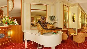 Une chambre luxueuse, agrémentée d’un grand piano, d’une statue et de meubles élégants.