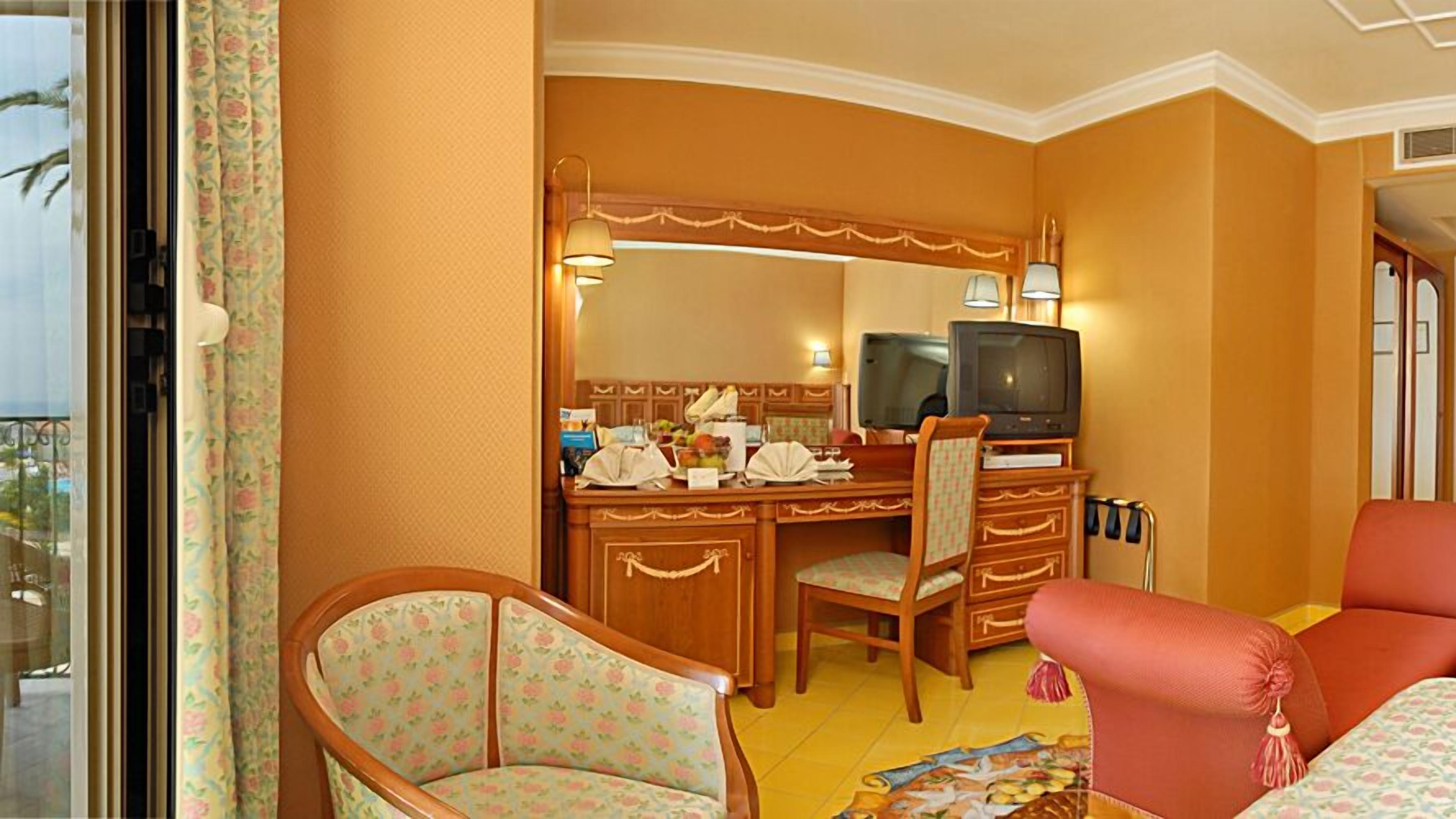 Una habitación de hotel con un escritorio de madera, un televisor, una silla y una cama.