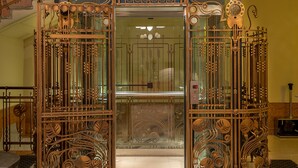 Una entrada imponente con intrincados detalles de hierro forjado y un vidrio que da a una escalera.