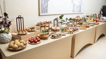 A buffet table with various food items and a vase of flowers.