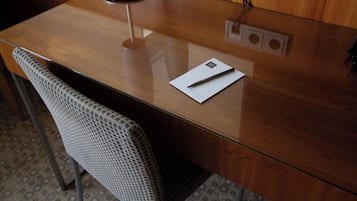 Un escritorio de madera con una superficie de cristal, una silla y un bolígrafo sobre un papel.
