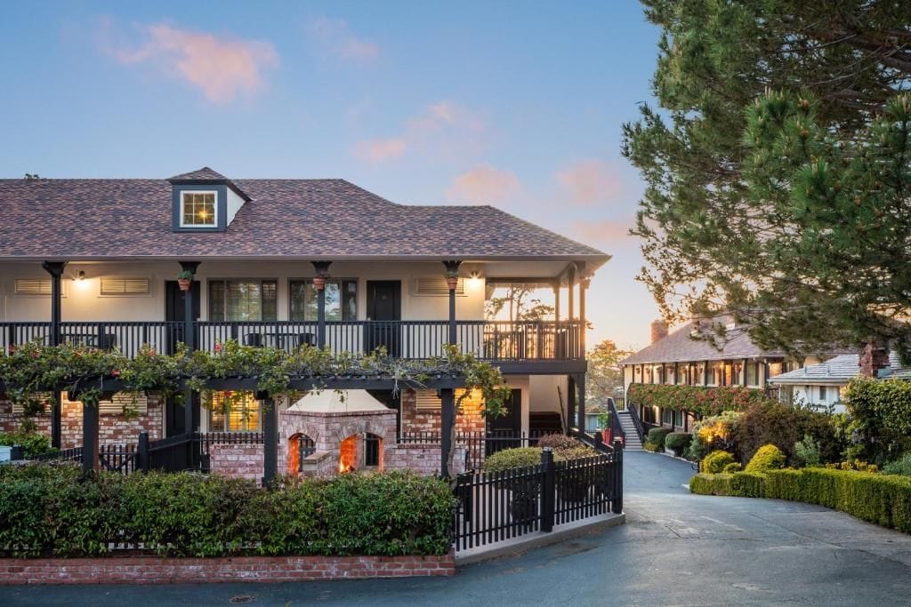 A two-story building with a balcony, a stone fireplace, and a well-maintained garden.