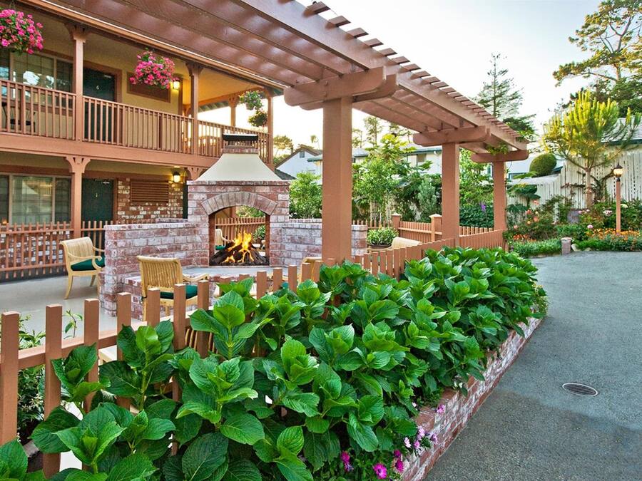 A hotel with a brick fireplace, outdoor seating, and a garden area.