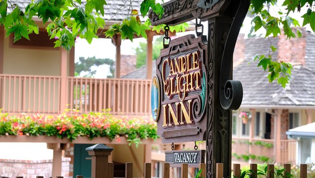Une enseigne en bois indiquant « Candlelight Inn » avec une étiquette « CHAMBRES LIBRES ».