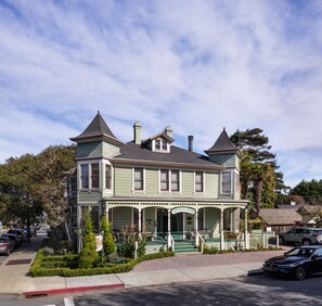 A Victorian-style hotel with a green facade, two towers, and a covered porch.