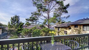 A balcony with a metal table and a vase of yellow flowers.