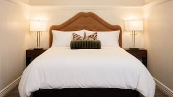 A hotel room with a large bed, two bedside tables, and lamps.