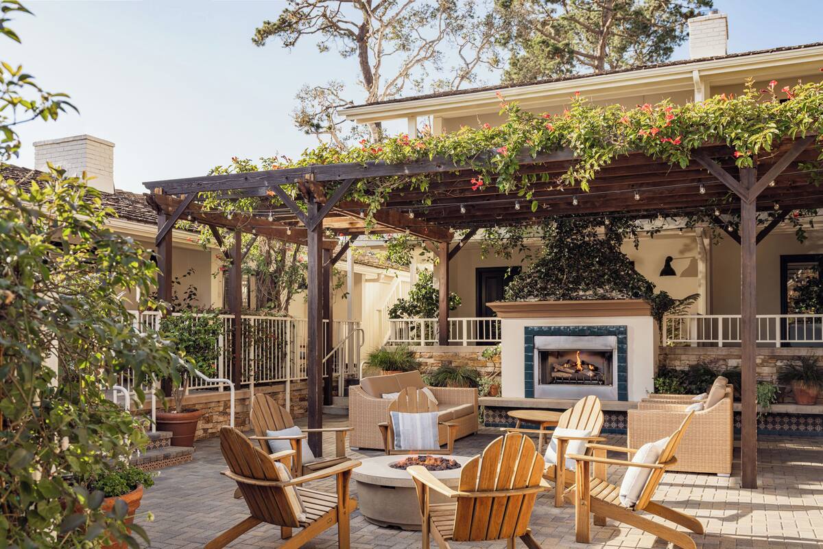 Une terrasse extérieure avec des fauteuils Adirondack, un foyer et une cheminée en pierre.