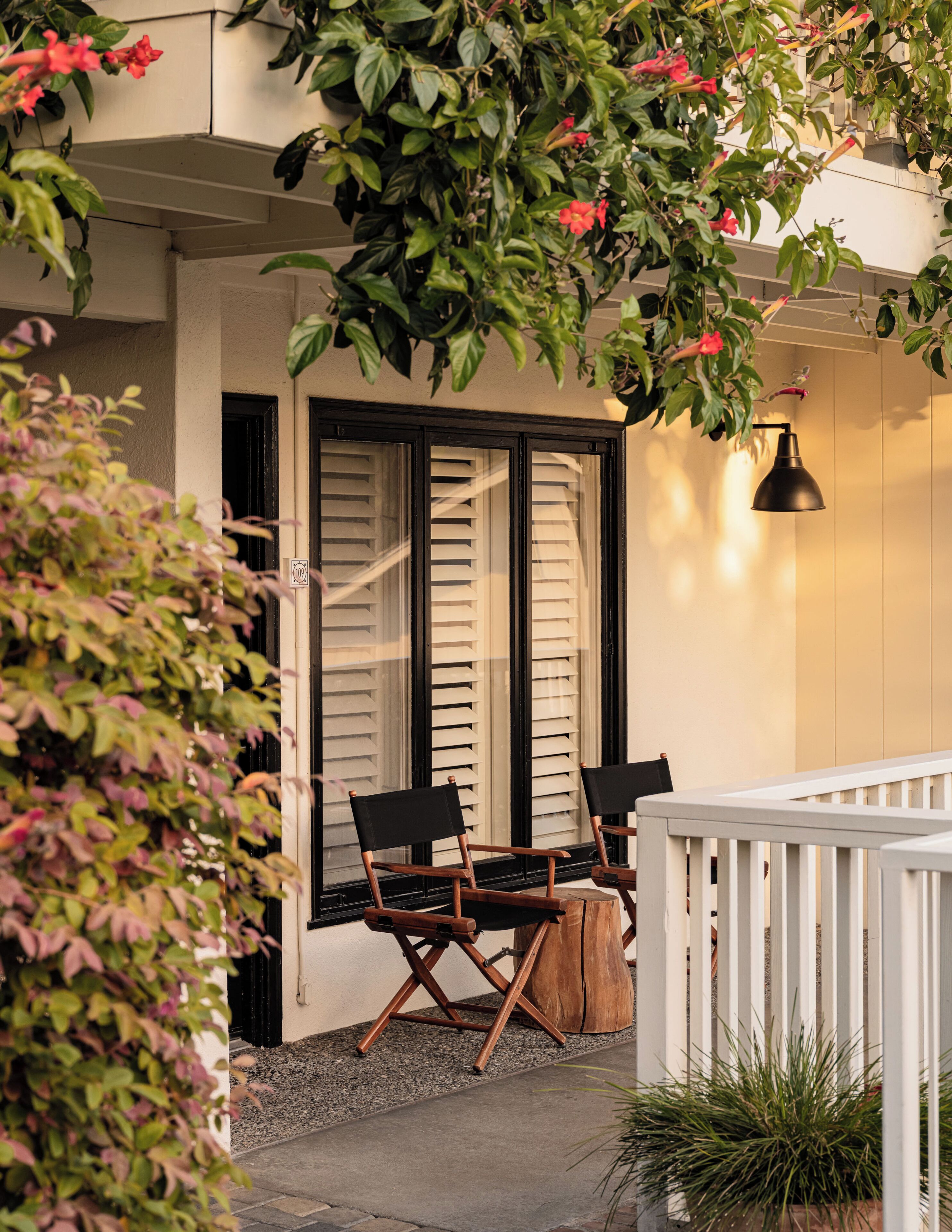 A balcony with two chairs, a hanging light fixture, and a white railing.