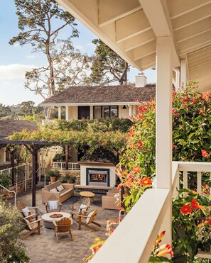 A covered patio with outdoor furniture, a fireplace, and a view of a house with a tiled roof.