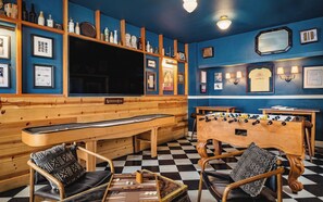 A bar area with a foosball table, billiards table, and seating.