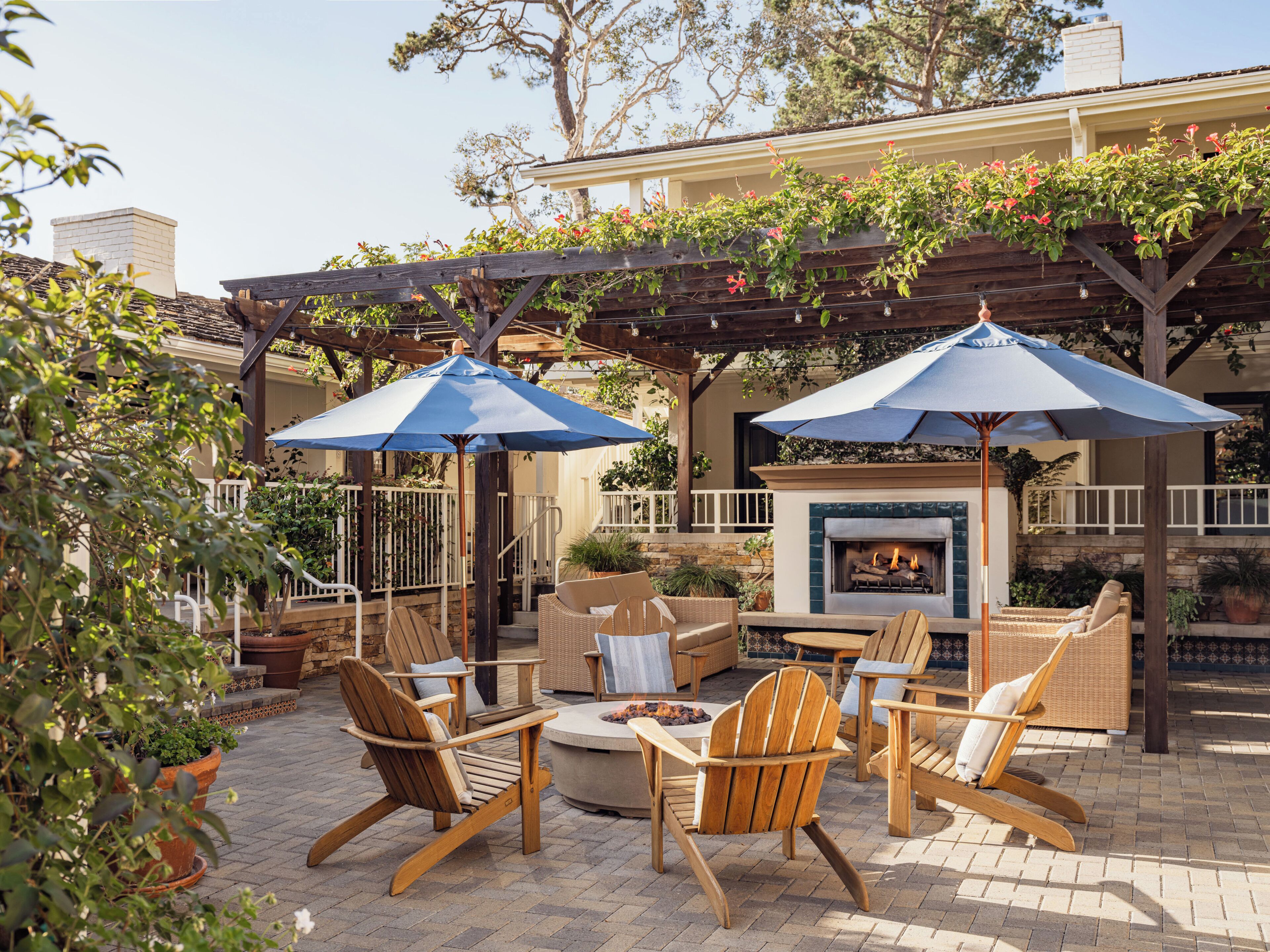 A patio area with outdoor furniture, a fireplace, and umbrellas.