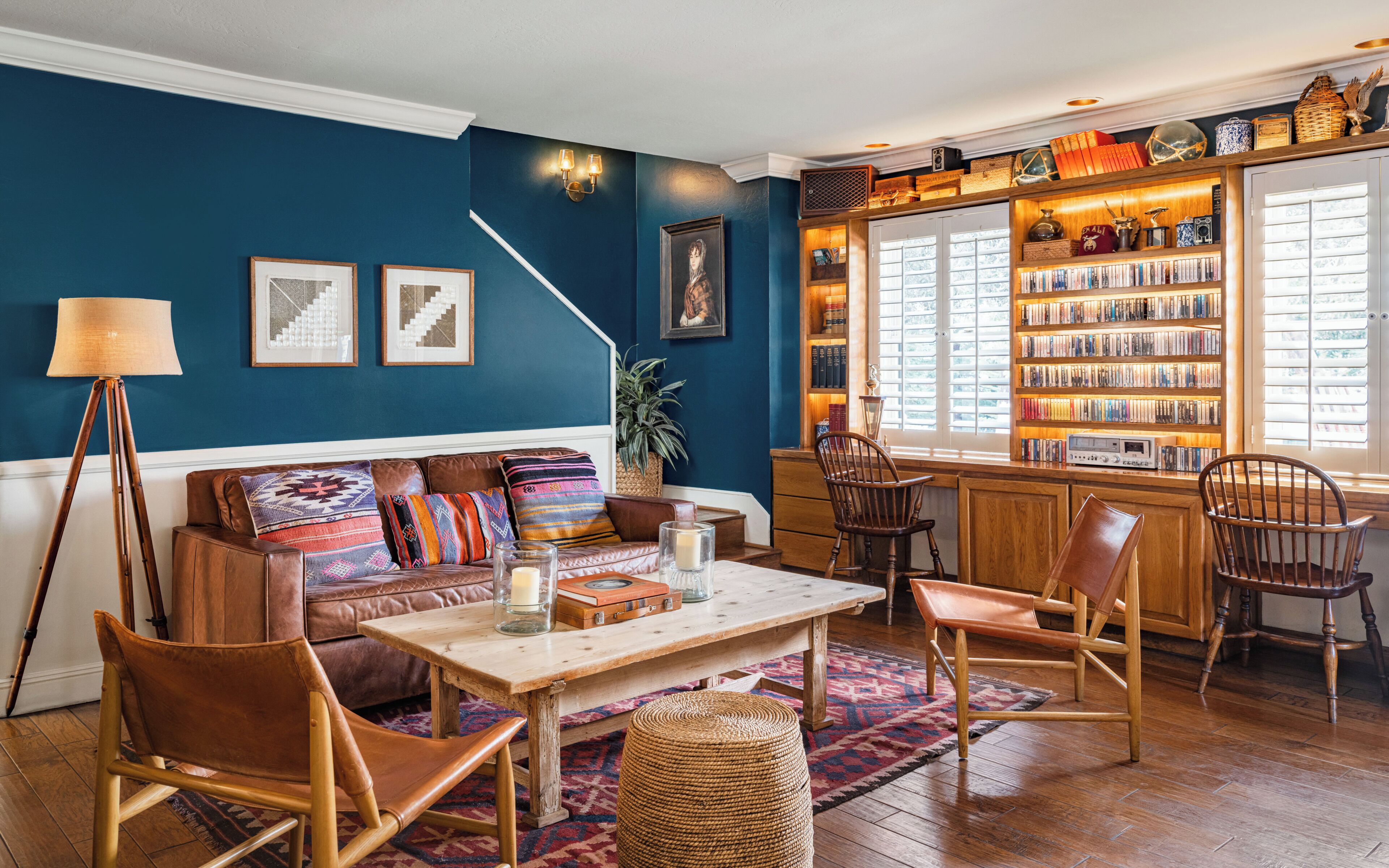 A cozy living room with a blue wall, a bookshelf, a coffee table, and a seating area.