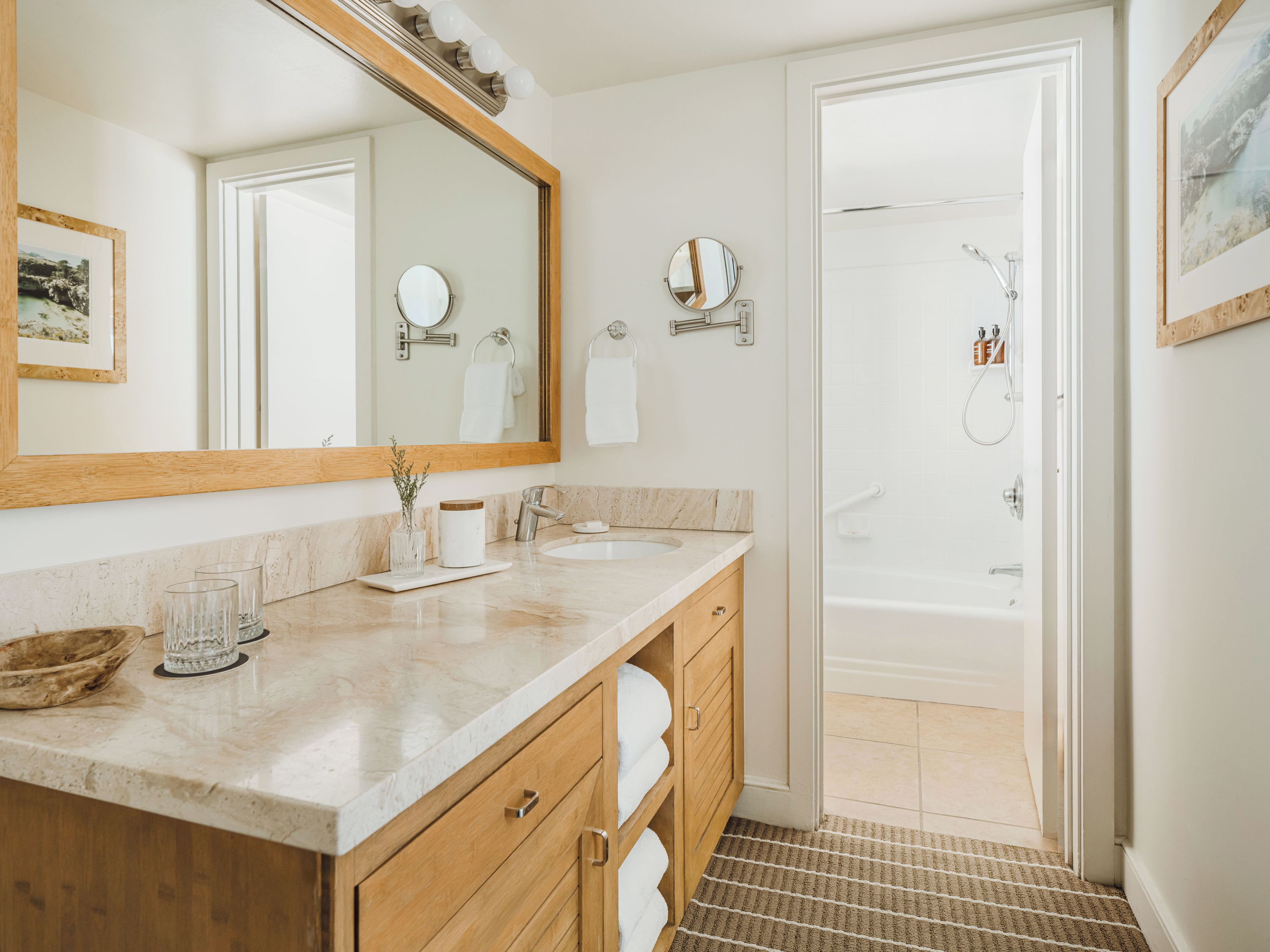 A bathroom with a large mirror, a sink, a shower, and a towel rack.
