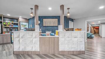 A reception area with a marble counter, wooden cabinets, and a wall-mounted artwork.