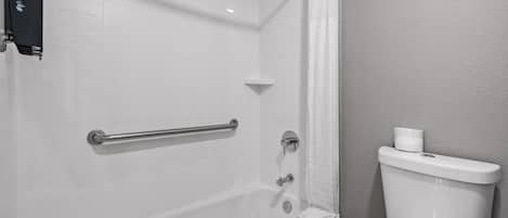 A bathroom with a bathtub, a toilet, and a shower curtain.