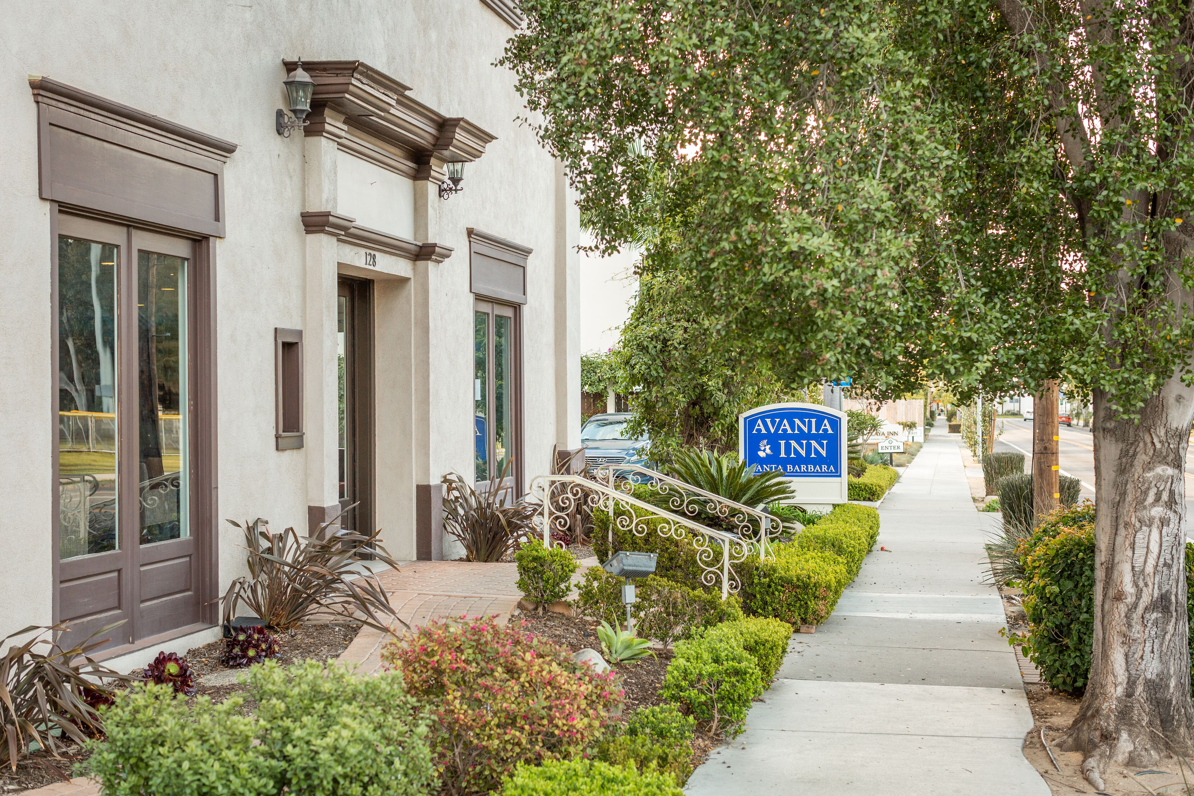 A building with a sign reading "AVANIA INN" and a well-maintained sidewalk with plants and a railing.