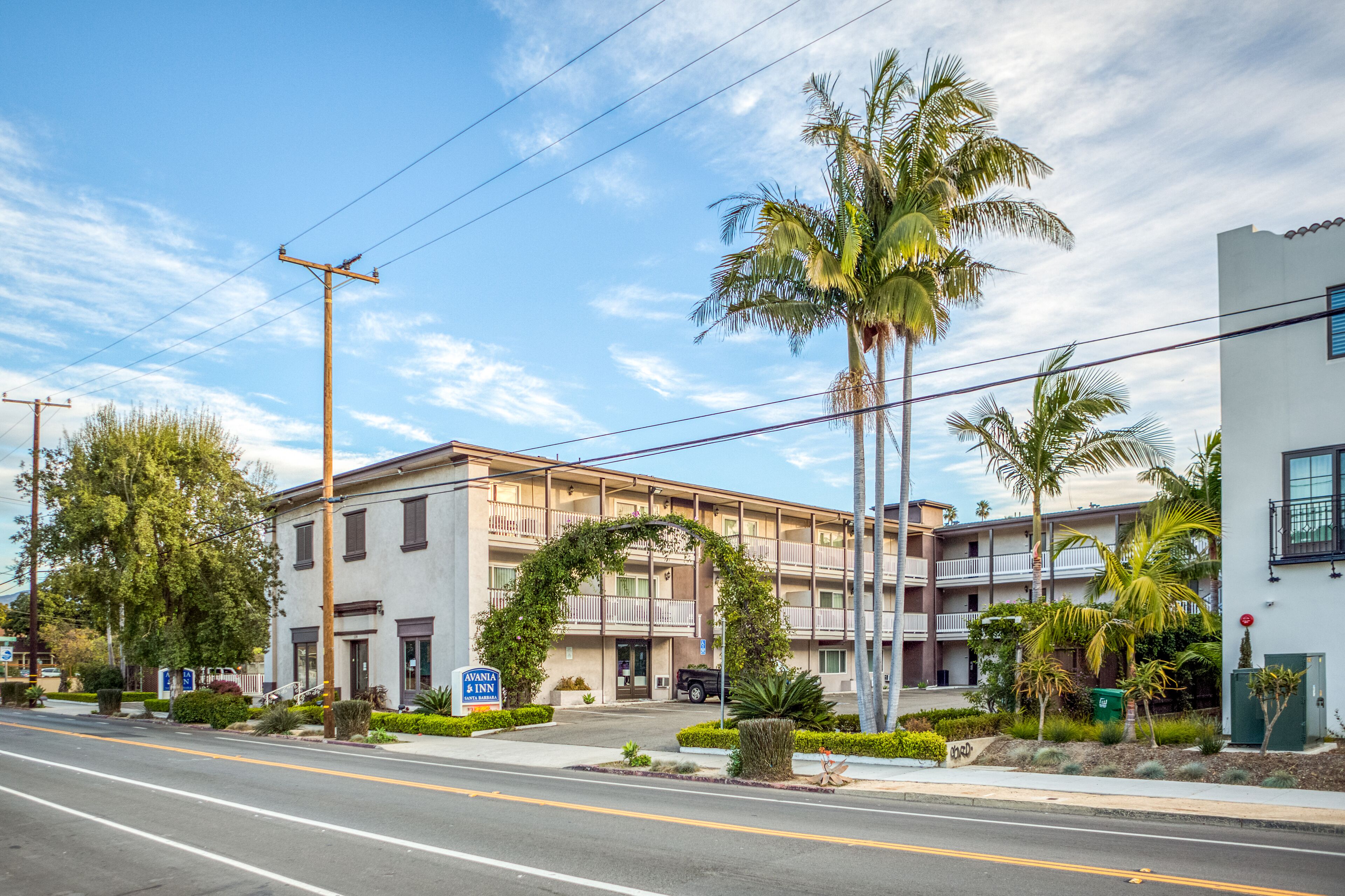 Un motel de varios pisos con un arco central, palmeras y un cielo despejado.