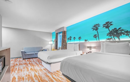A hotel room with a large bed, a sofa, a desk, and a nightstand.
