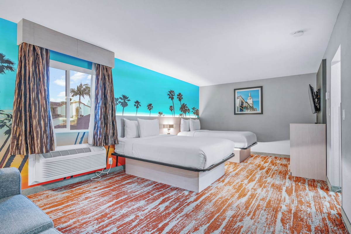 A modern hotel room with a large bed, a desk, and a view of palm trees through the window.